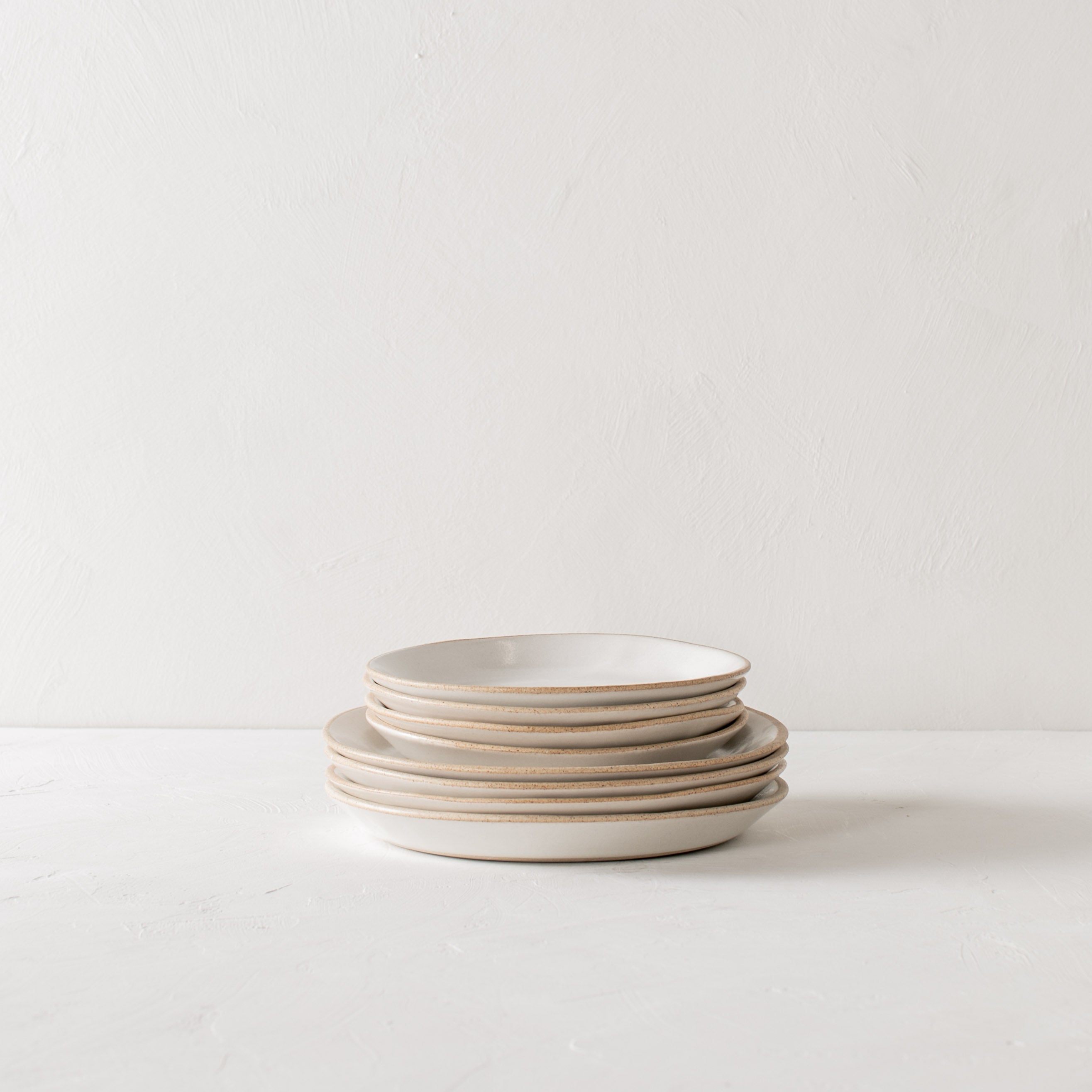 Minimal white ceramic plates stacked, four salad plates stacked on four dinner plates. Handmade ceramic plates, designed and sold by Convivial Production, Kansas City ceramics.