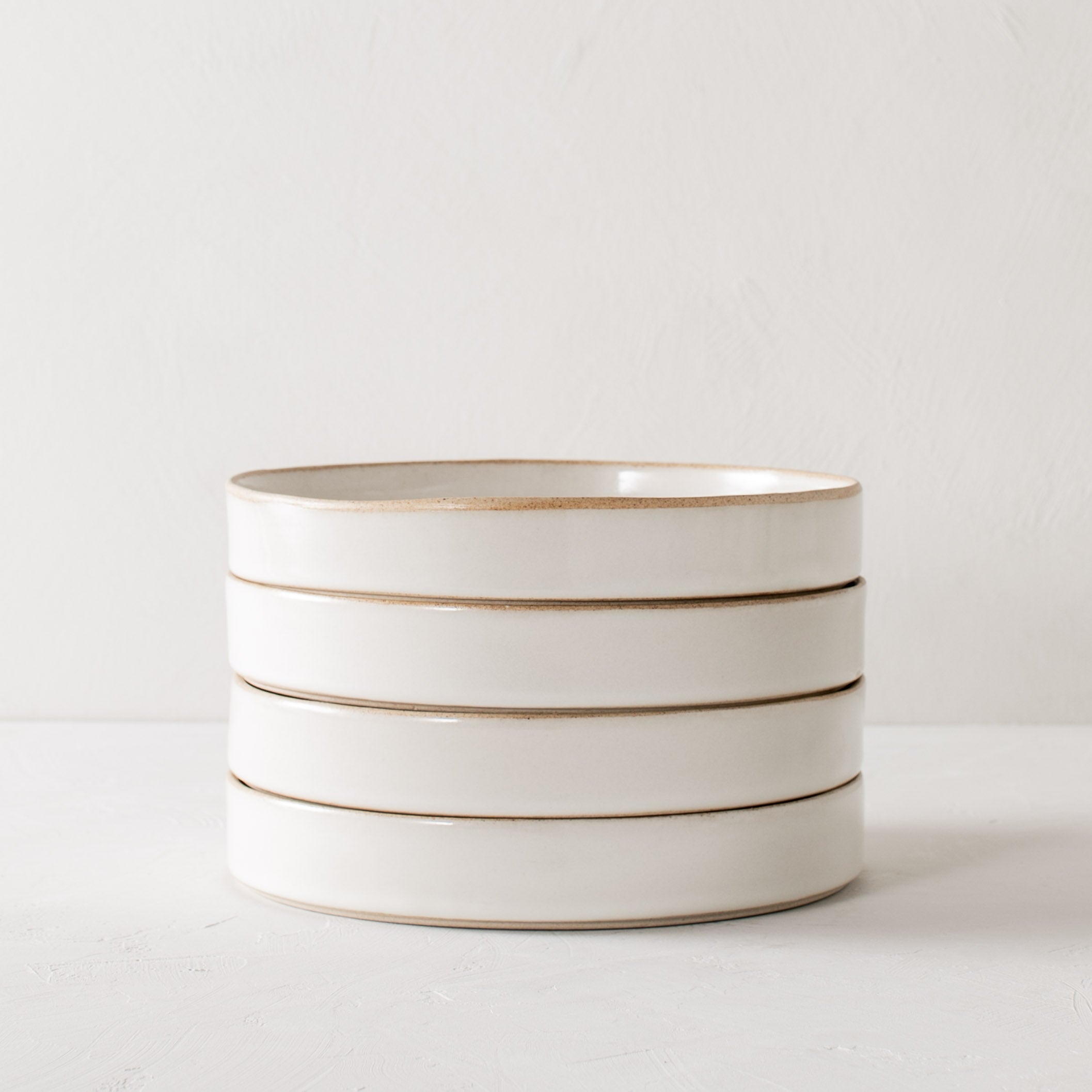 Stack of four minimal dinner dishes. Stackable dishes with exposed stoneware rim and base. Handmade stackable ceramic dishes designed and sold by Convivial Production, Kansas City ceramics. 