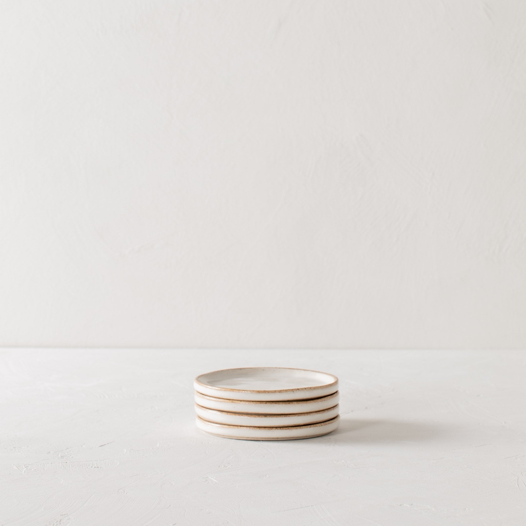 Stack of four white ceramic 4 inch side dishes. Dishes have exposed stoneware rims and bases. Handmade ceramic side dishes designed and sold by Convivial Production, Kansas City ceramics.