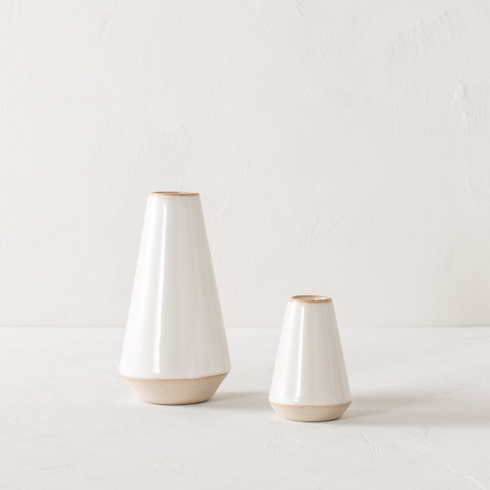 Two minimal white tapered bud vases side by side, seven inch and 4 in. Handmade ceramic bud vase designed and sold by Convivial Production, Kansas City ceramics.
