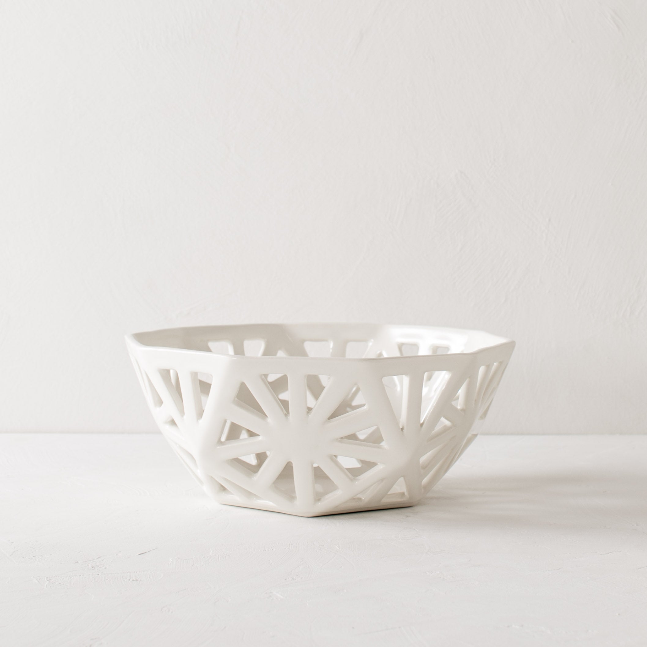 White geometric fruit bowl. Pentagon carved design with additional carved designs in the shape of slim right angle triangles. Designed and sold by Convivial Production, Kansas City Ceramics