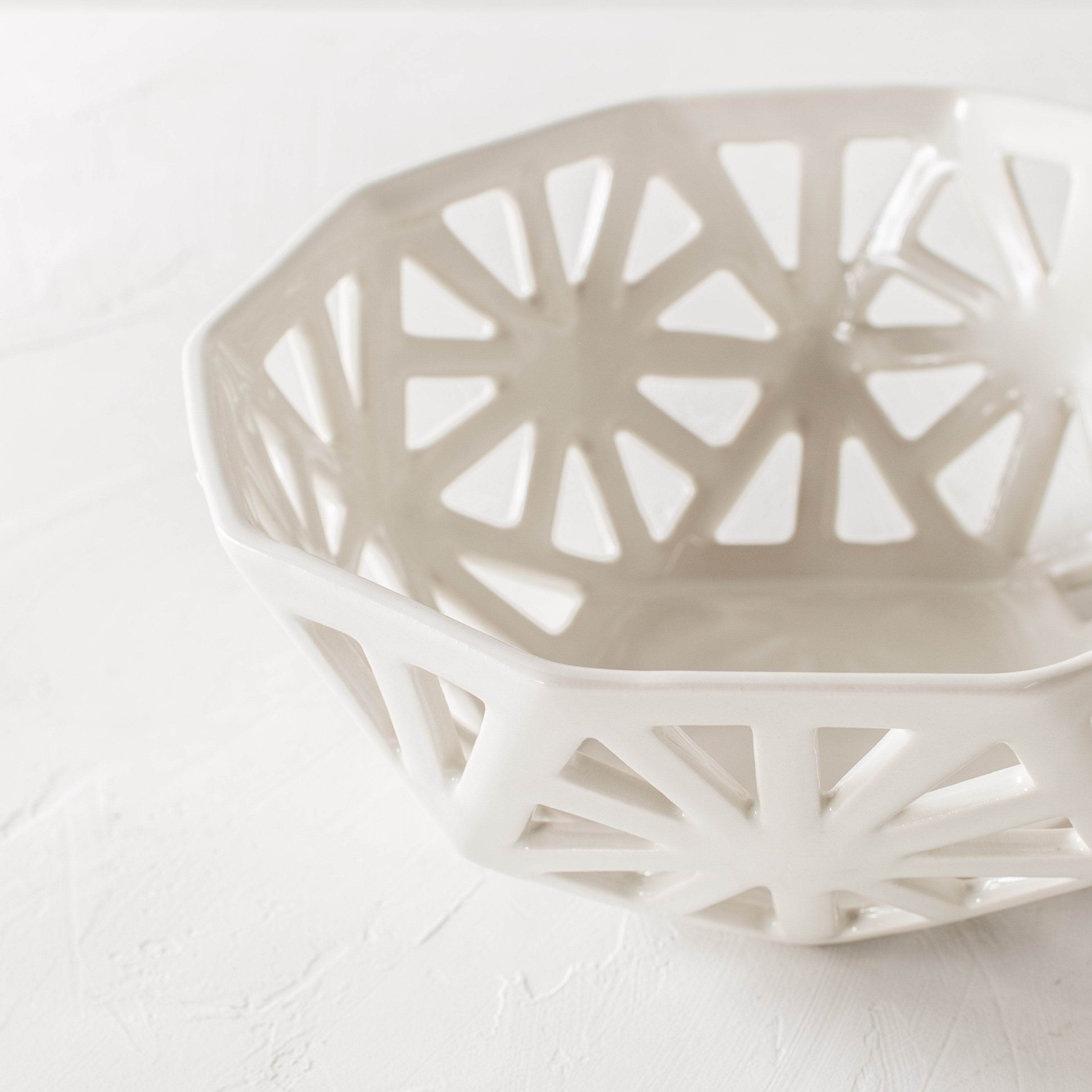 White geometric fruit bowl. Pentagon carved design with additional carved designs in the shape of slim right angle triangles. Close up detail images focusing on carving design. Designed and sold by Convivial Production, Kansas City Ceramics