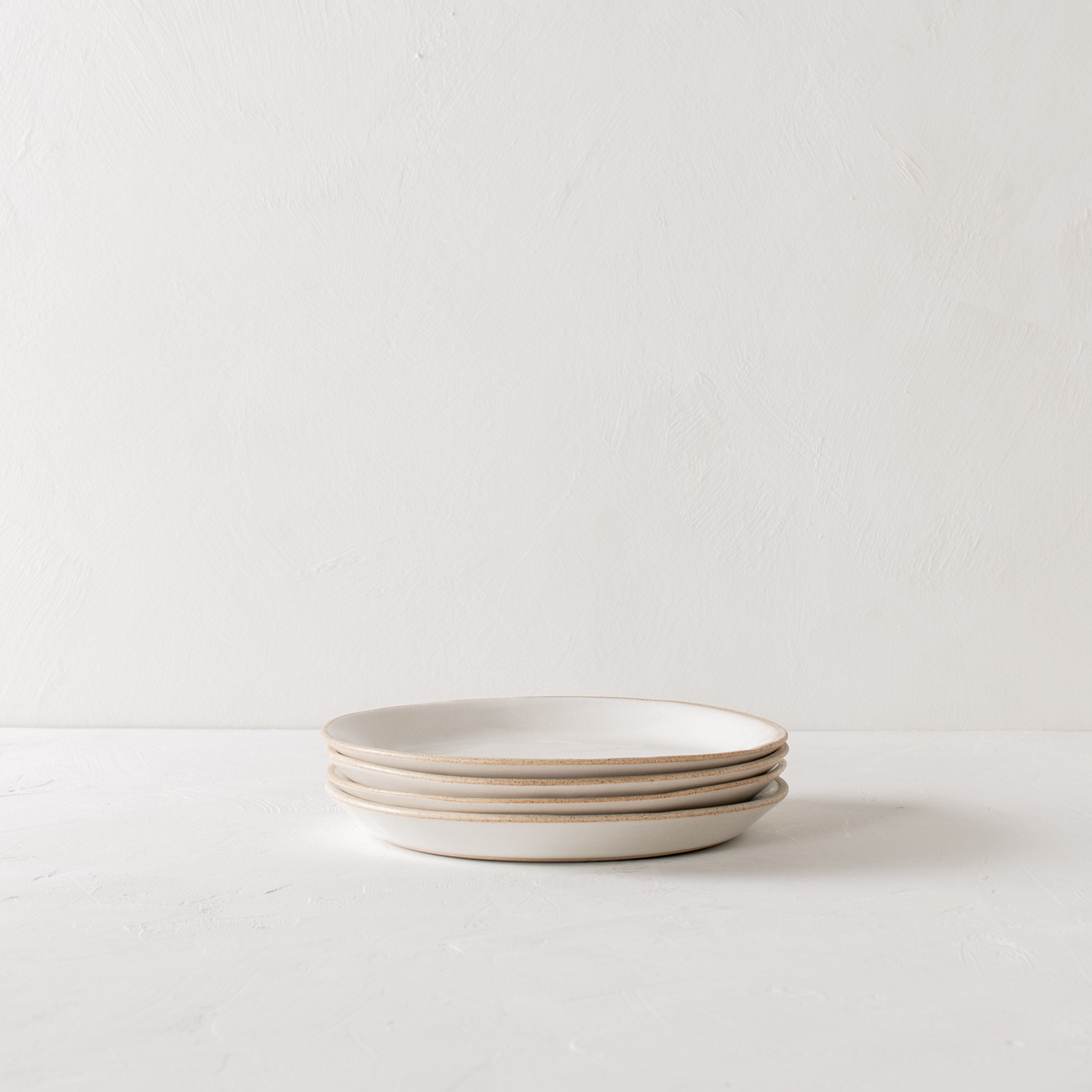 Minimal white ceramic plates stacked, four salad plates stacked. Handmade ceramic plates, designed and sold by Convivial Production, Kansas City ceramics.