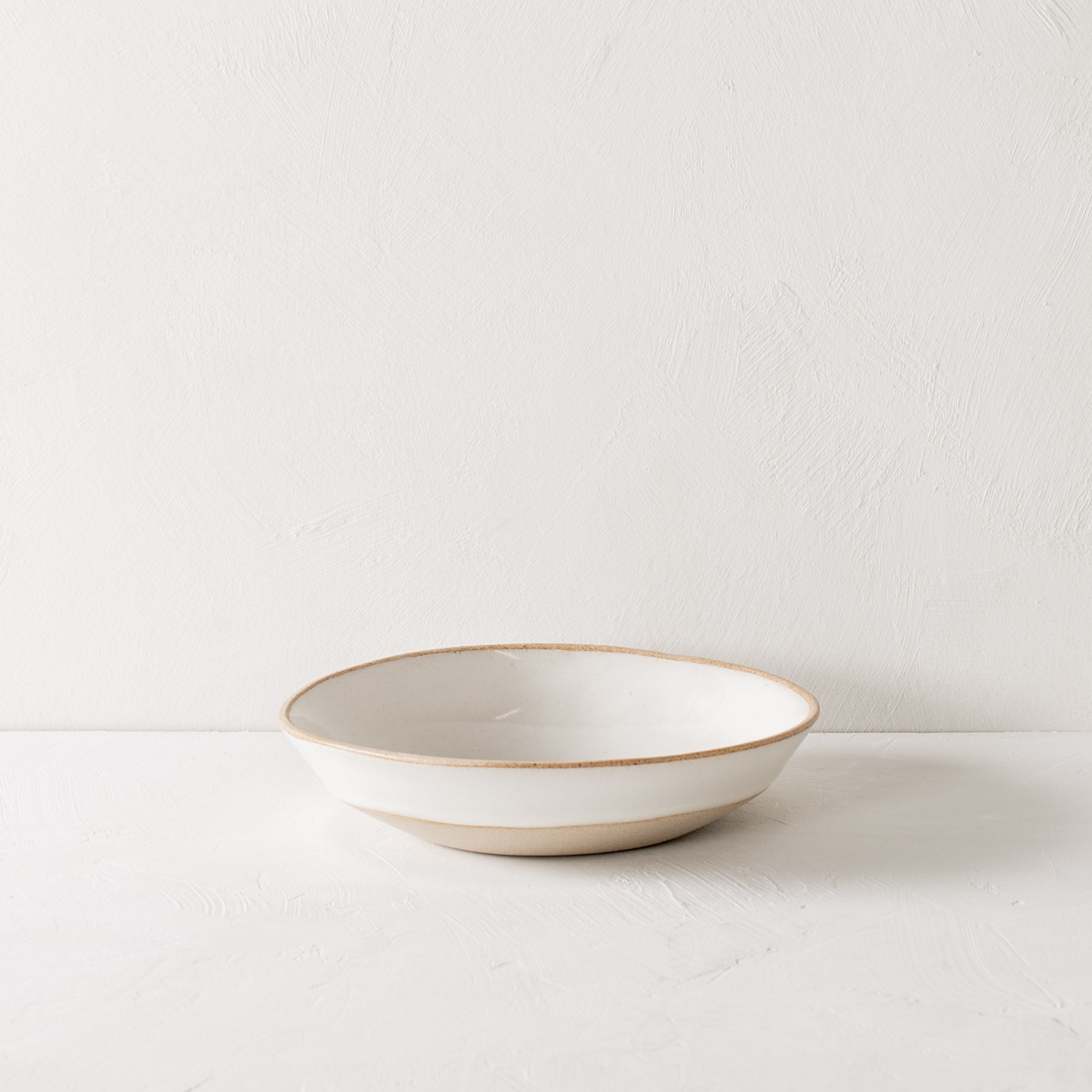 Minimal white pasta bowl. The pasta bowl has exposed stoneware rims and extended base. Handmade ceramic pasta bowl, designed and sold by Convivial Production, Kansas City ceramics.